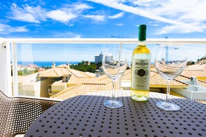 A balcony with a table, a bottle of wine, and two glasses. - Pine Hills - New Apartment Fuengirola (Fuengirola)
