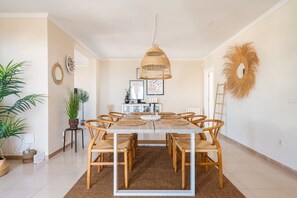 A dining area with a wooden table, wicker chairs, and a hanging light fixture. - Villa Sabine - Spectacular Sea View Villa in Capel (Benalmádena)