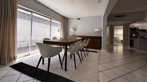 A modern hotel room with a dining area, large windows, and a kitchen visible in the background. - Charming 3-bedroom house in Tamarac. Minutes from Hardrock, Beaches, & Shopping (Tamarac)