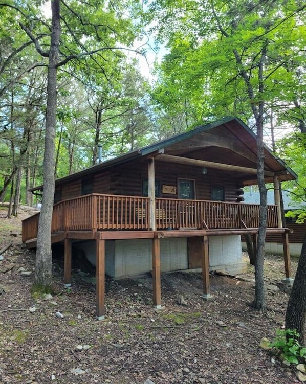 Eine HolzhĂŒtte mit Veranda und ĂŒberdachter Terrasse, umgeben von BĂ€umen.