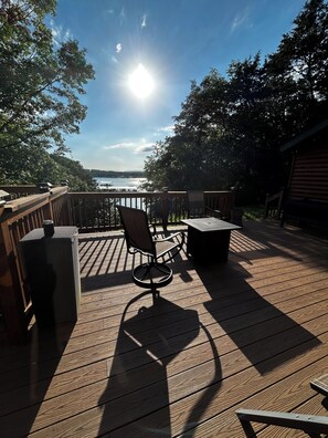 A wooden deck with a table and chairs, overlooking a body of water.