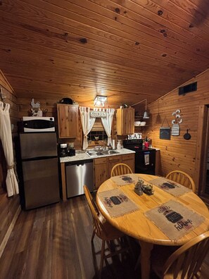A wooden cabin interior with a kitchen, dining area, and a cozy atmosphere.