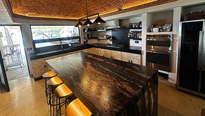 A modern kitchen with a large island, bar stools, stainless steel appliances, and a brick ceiling. - Unique Lakefront estate, Santiago NL minutes from Monterrey, villa la Boca (Santiago)