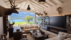 A spacious living room with a large TV, comfortable seating, a fireplace, and a scenic view of mountains and a lake. - Unique Lakefront estate, Santiago NL minutes from Monterrey, villa la Boca (Santiago)
