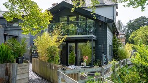 Ein modernes Haus mit einem großen Panoramafenster, einem Holzzaun und einem Garten.