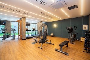 Ein Fitnessstudio mit Laufbändern, Kraftgeräten und einer Bank.