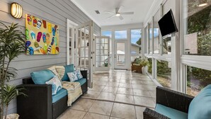 A covered patio with wicker furniture, a wall-mounted TV, and a ceiling fan. - Grand Floridian|Heated Pool|Walk to Beach|Sleeps 12 (St. Augustine)