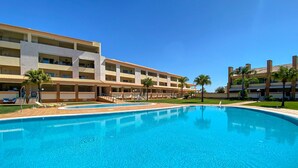 A hotel with a swimming pool, multiple balconies, and palm trees. - Millennium Plaza by Hsrentals (Loulé)