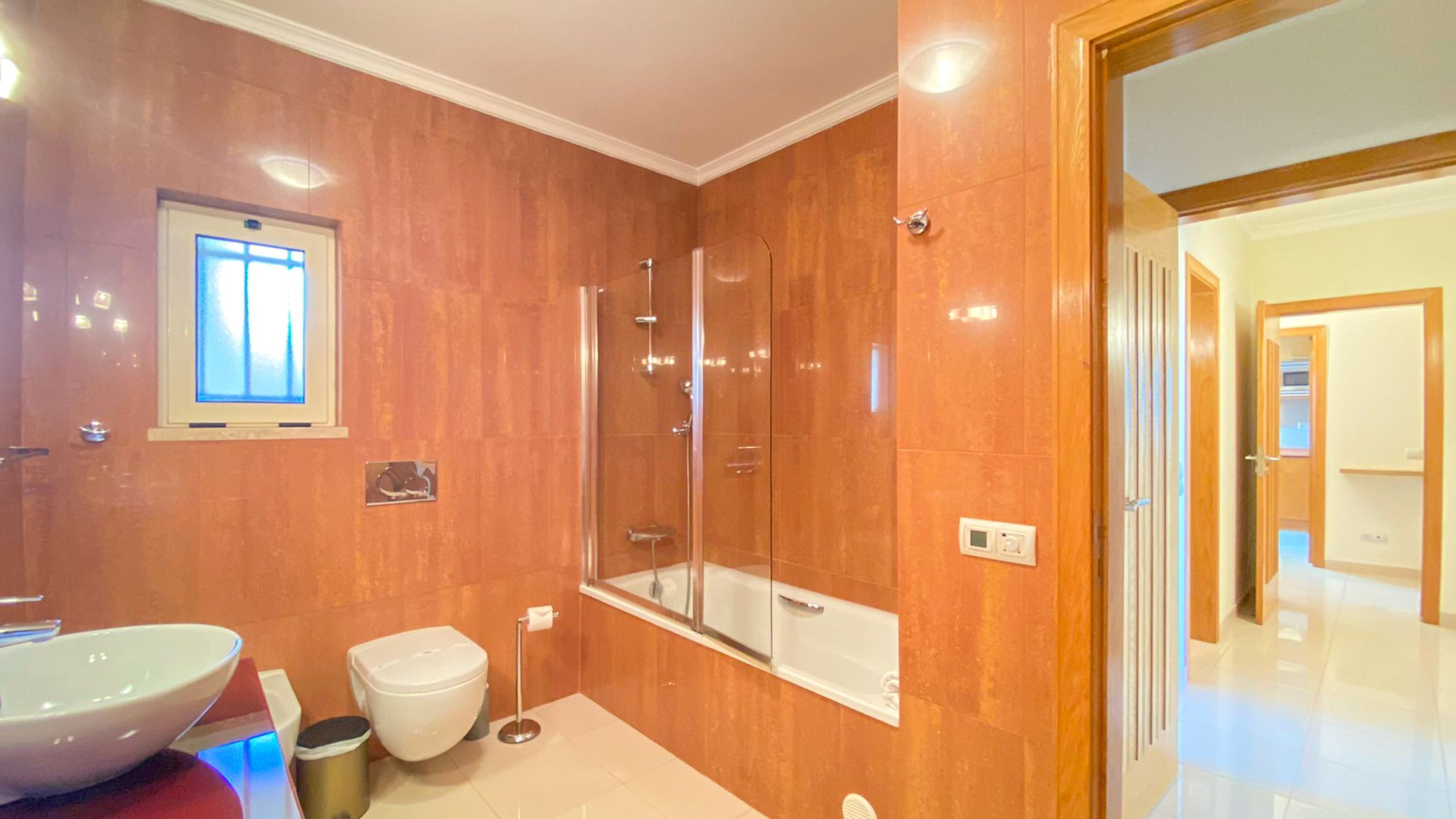Ein Badezimmer mit großem Spiegel, Waschbecken in Weiß, Toilette und Duschkabine.