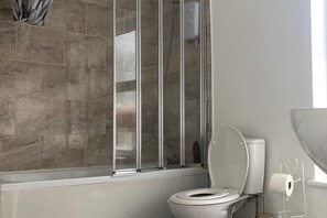 A bathroom with a shower enclosure, a toilet, and a toilet paper holder.