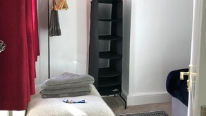 A room with a bed, a black shelving unit, a red curtain, and a small rug. - 3 Bed House Sleeps 6 - Smart Tv - Free Parking (Liverpool)