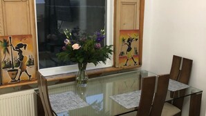 A dining area with a glass table, chairs, and a vase with flowers. - 3 Bed House Sleeps 6 - Smart Tv - Free Parking (Liverpool)
