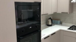 A compact kitchen with a built-in oven, a stovetop, and a kettle. - 3 Bed House Sleeps 6 - Smart Tv - Free Parking (Liverpool)