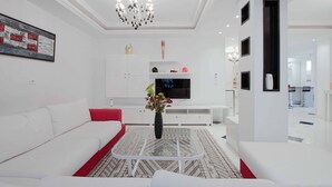 Una sala de estar moderna con un sofá blanco, una mesa de centro y un televisor.