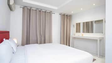 A hotel room with a bed, a bedside table with a lamp, a mirror, and a wall-mounted air conditioner.
