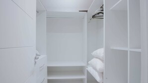 Un armario vestidor blanco con estantes y espacio para colgar.