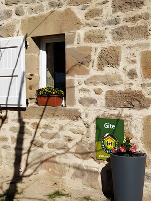A stone building with a window, a door, and a sign that reads 'Gîte.'