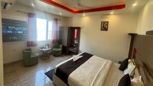 Quarto de hotel com cama, televisão, escrivaninha e cadeira.
