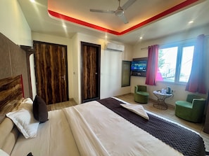 A hotel room with a bed, a television, a ceiling fan, and a window with curtains.