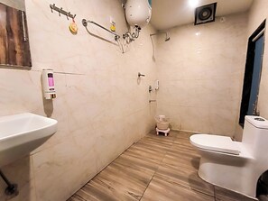 Baño con lavamanos, inodoro, ducha y secador de manos.