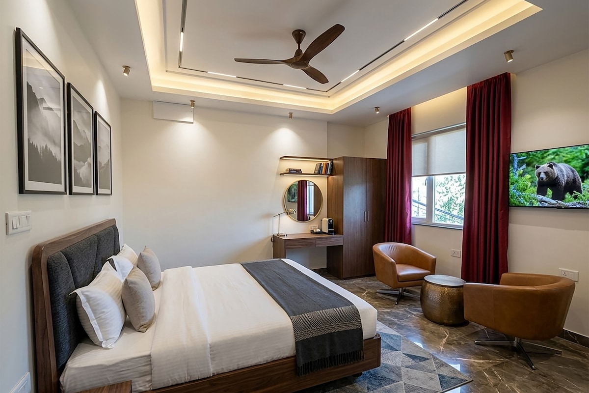 Una habitación de hotel moderna con cama, escritorio, silla, televisor y una obra de arte en la pared.