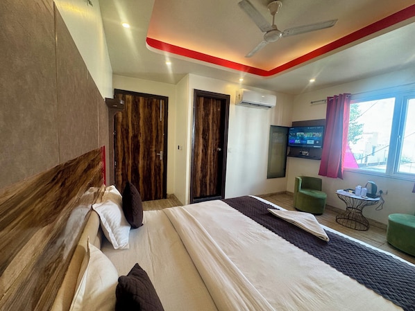 A hotel room with a bed, a television, a desk, and a window.