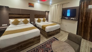Quarto de hotel com duas camas, televisão, ventoinha no teto e uma parede vermelha de destaque.