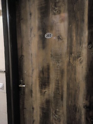 Une porte en bois avec une plaque indiquant le numéro de la chambre : 203.