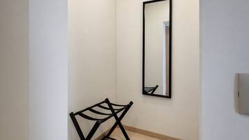 Un couloir avec un miroir, un banc en métal noir et un plancher de couleur claire.
