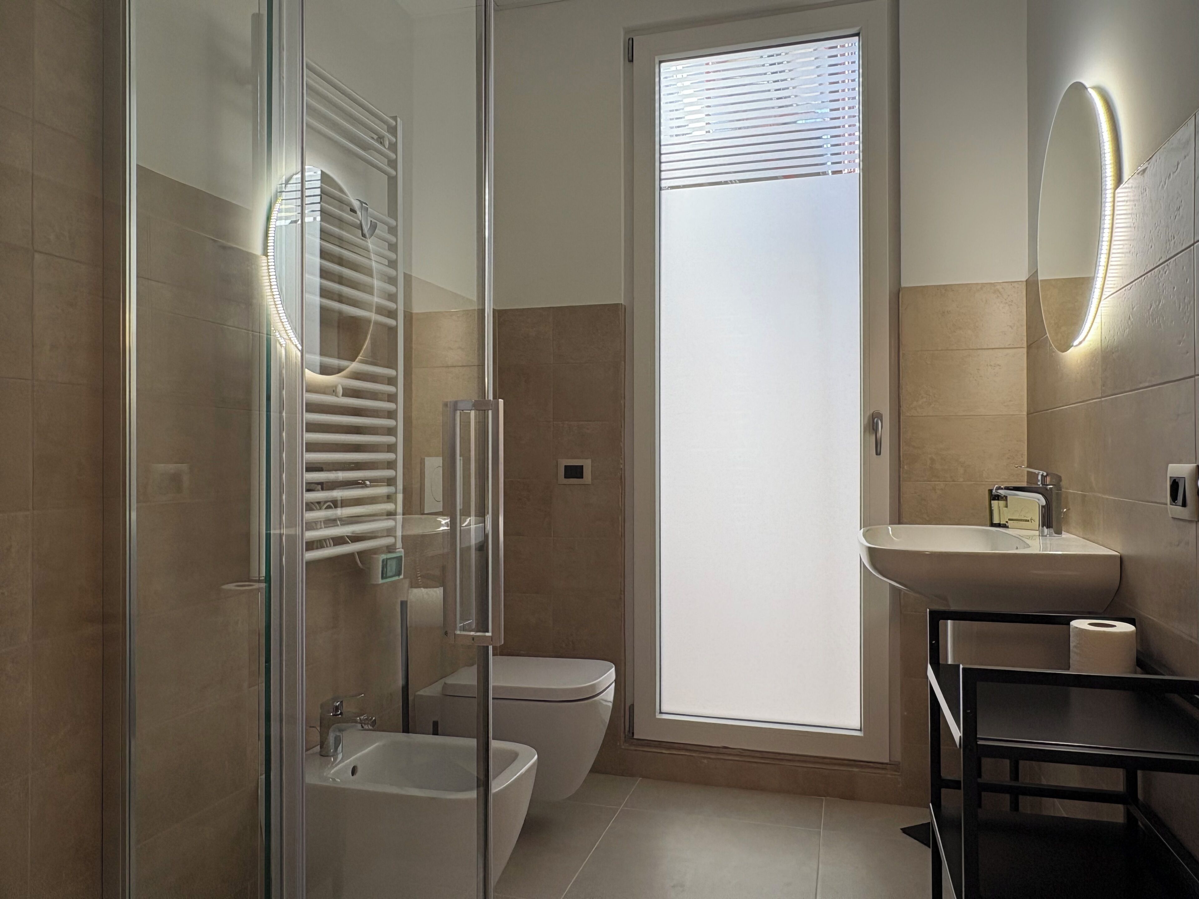Une salle de bain moderne dotée d’une douche à parois de verre, de toilettes, d’un bidet et d’un lavabo.