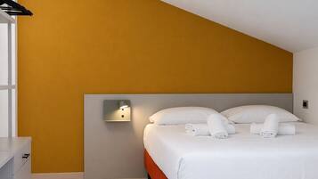 Habitació d'hotel amb llit, taulell de nit, làmpada de paret i armari.