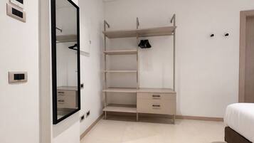 Une chambre à coucher avec un lit, une armoire avec des étagères, un miroir et une porte.