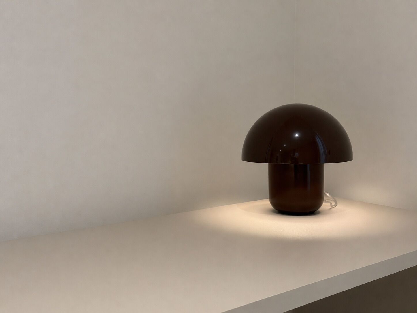En moderne lampe med kuppelformet skærm på en hvid overflade.