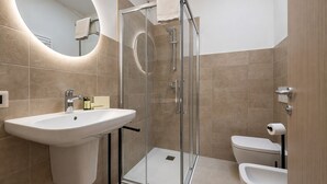 Une salle de bain moderne avec une douche à parois de verre, un lavabo blanc et des toilettes.