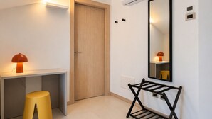 Une chambre moderne avec une porte en bois, un bureau avec une lampe, un miroir et un présentoir en métal noir.
