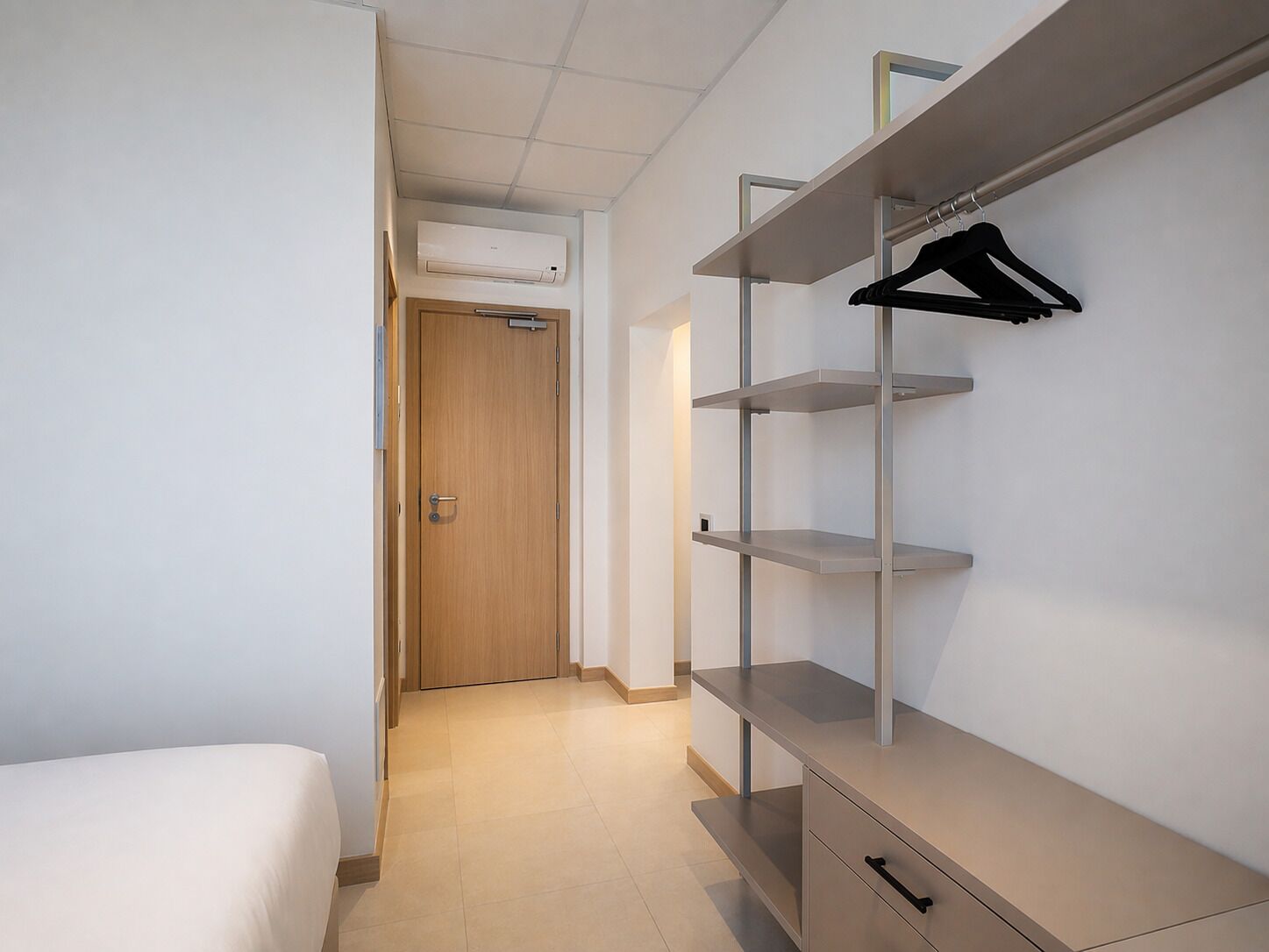 Un dormitorio con una cama, un armario con estantes y una puerta que da a otra habitación.