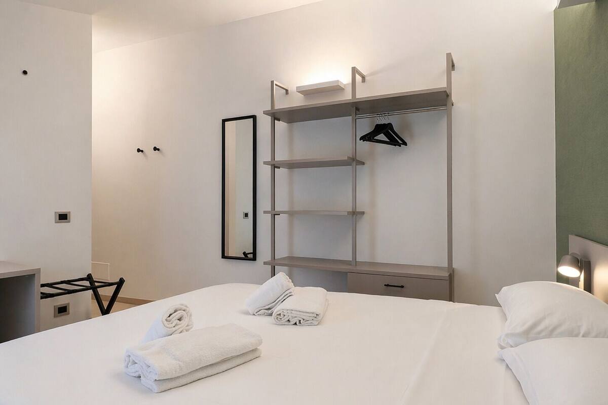 A hotel room with a bed, a wardrobe, a mirror, and a desk.