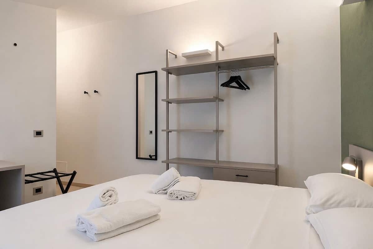 Une chambre d’hôtel avec un lit, une armoire, un miroir et un bureau.