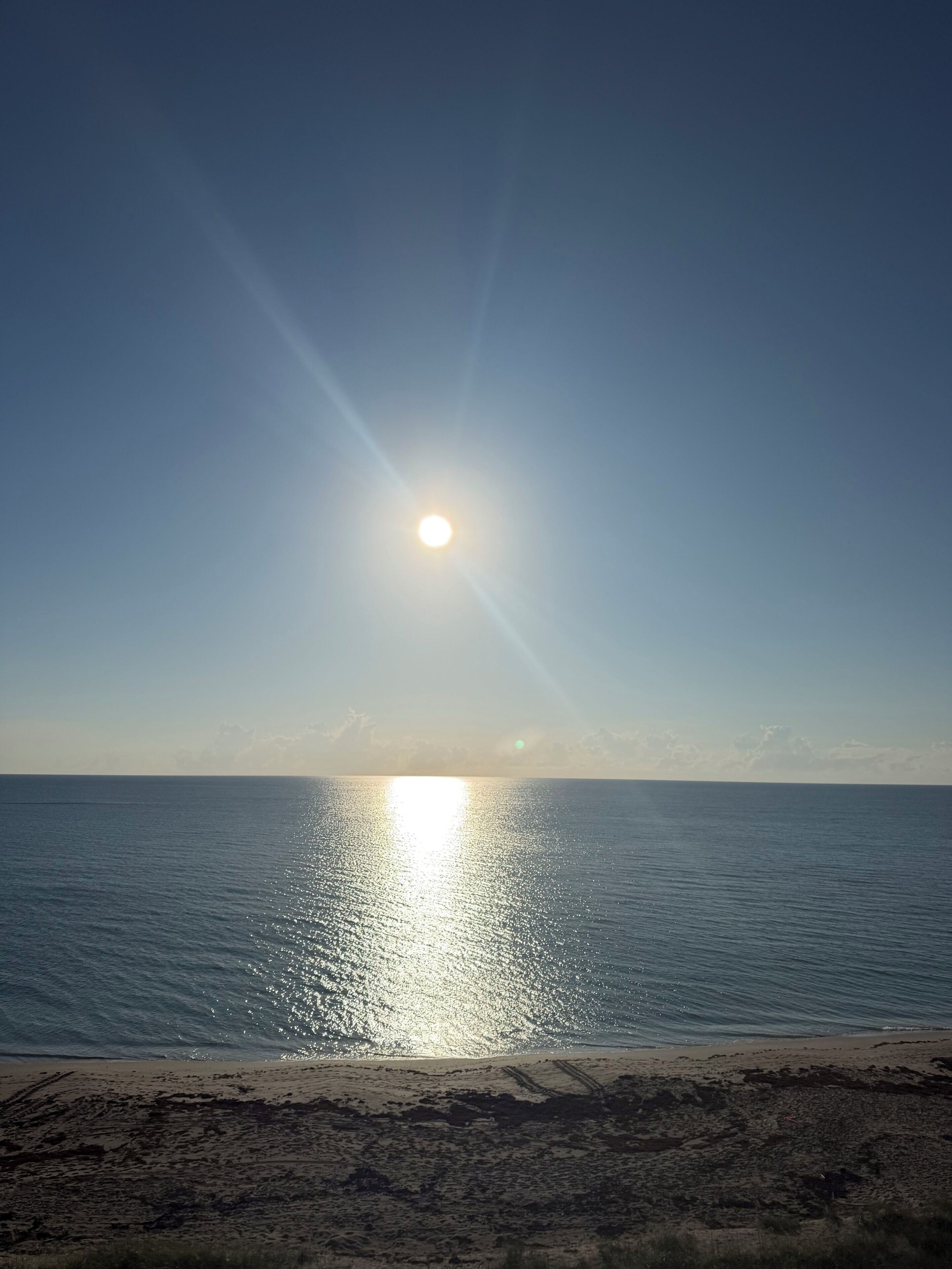 Ein Strand mit der Sonne, die sich im Wasser spiegelt.
