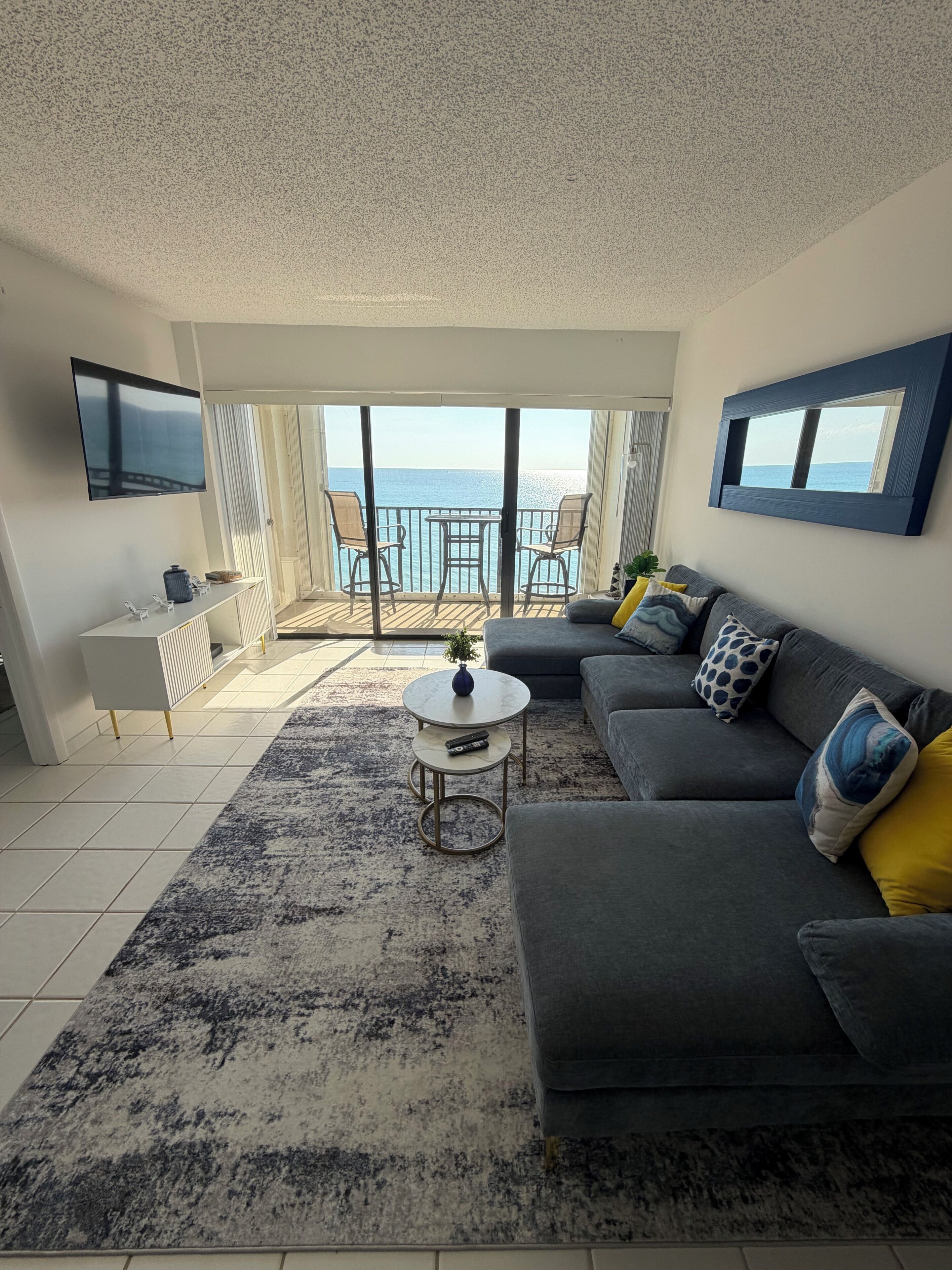 A modern living room with a grey sofa, a coffee table, and a TV mounted on the wall.
