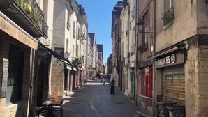 Eine enge Kopfsteinpflasterstraße gesäumt von historischen Gebäuden, von denen einige Schilder zeigen.