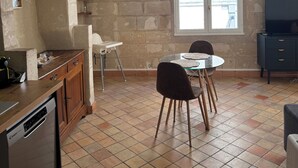 Eine Küche mit Geschirrspüler, einem Esstisch mit Stühlen, einem TV-Schrank und einem Fenster mit Blick.