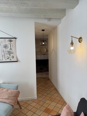 Een kamer met een lichtblauwe bank, een roze plaid, een aan de muur hangend schilderij en een betegelde vloer.