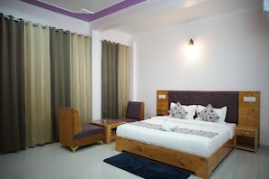 Une chambre à coucher comprenant un lit, une chaise, une petite table, une table de chevet et un luminaire fixé au mur.
