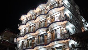 Un edificio de varios pisos con balcones, ventanas y una fachada bien iluminada durante la noche.