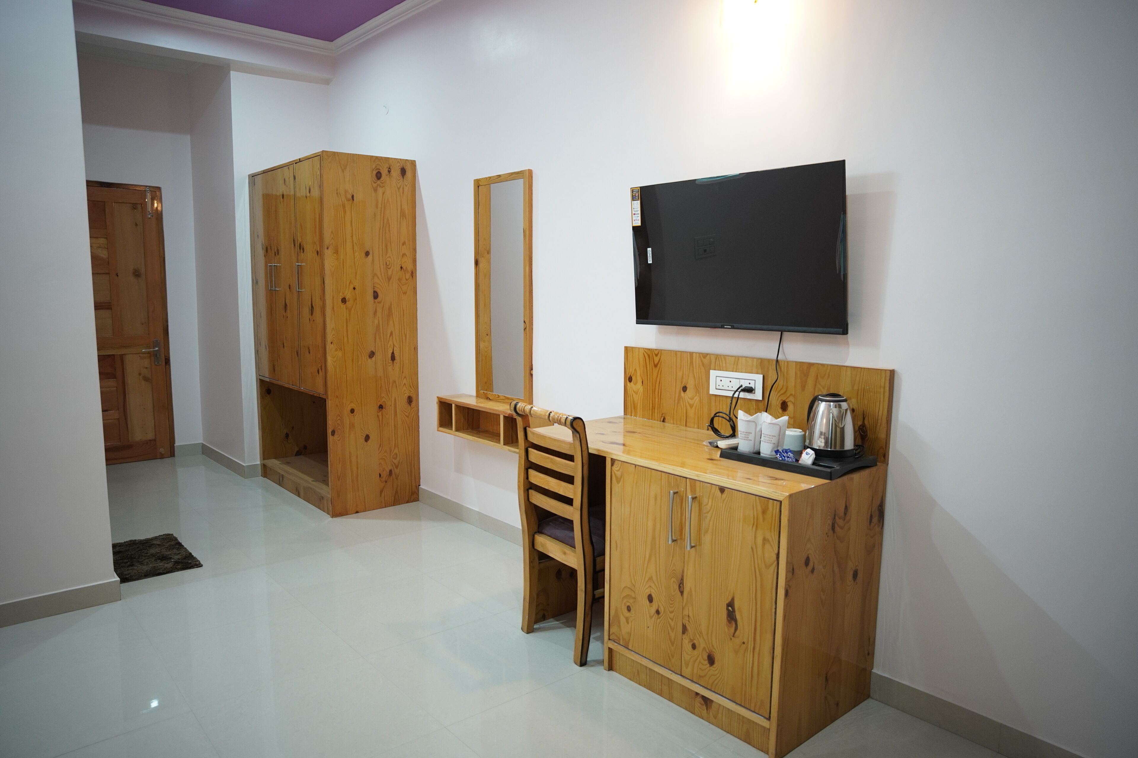 Habitació amb escriptori de fusta, cadira, televisió i armari.