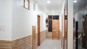 Un pasillo con suelo de madera, paredes blancas y una puerta que da a una habitación.