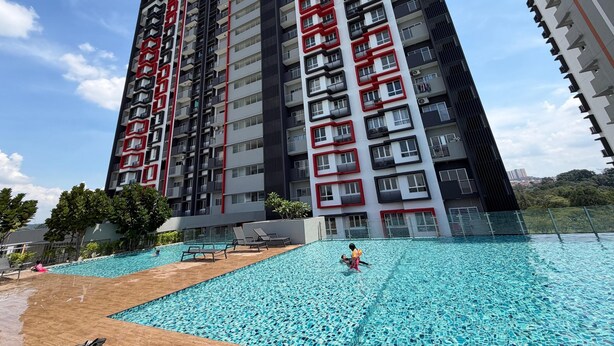 A high-rise building with multiple balconies, a swimming pool, and a clear sky. - Sufi Homestay for Muslim only (Nilai)