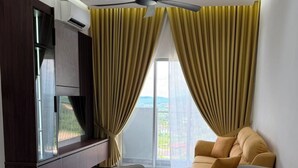 A modern living room with a sofa, a TV, and a ceiling fan. - Sufi Homestay for Muslim only (Nilai)
