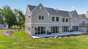 A two-story house with a large patio, a covered outdoor seating area, and a garage.
